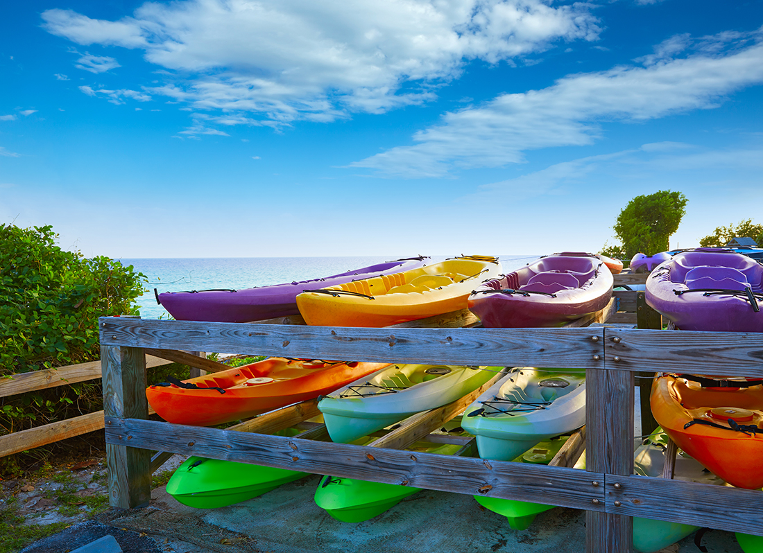 Nine colorful kayaks on a rack at the beach.